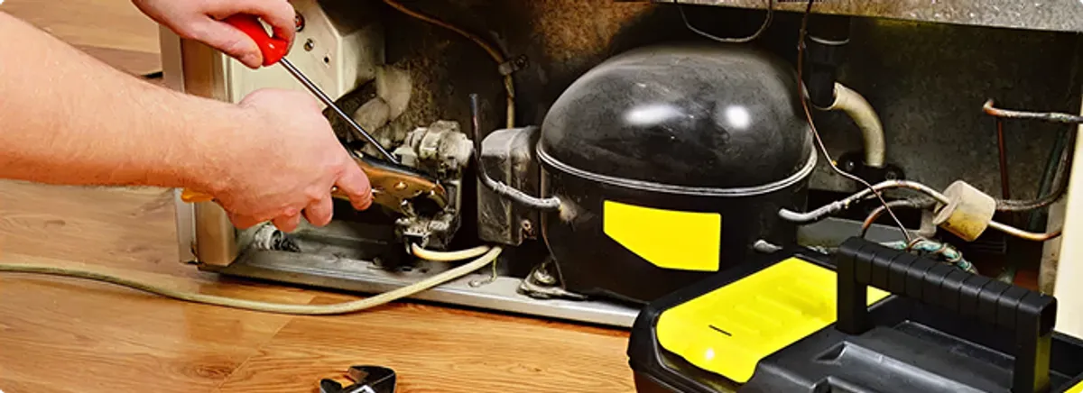 Refrigerator repair technician fixing the compressor and wiring in Bothell, WA